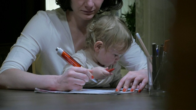 母亲写信时，婴儿坐在膝盖上视频素材