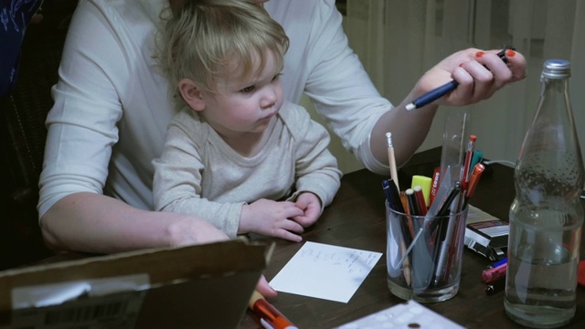 妈妈挑选铅笔让宝宝趴在腿上写字视频素材
