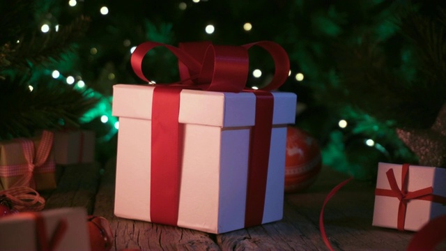 圣诞礼物和装饰品放在旧木桌上，圣诞彩灯作为背景视频下载