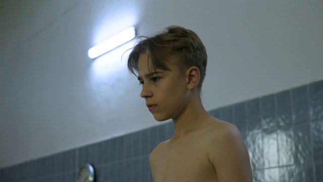 年轻的害怕，困惑的少年看着水在老学校游泳池和思考他应该做什么视频下载