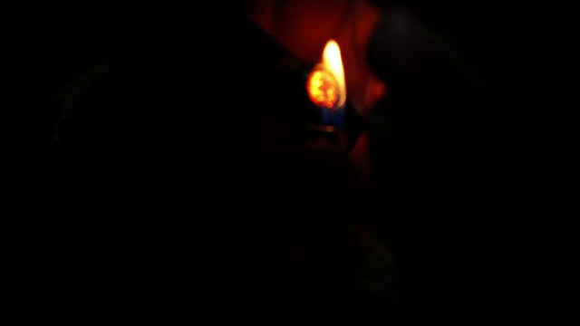 一个男人燃烧和吸烟斗在晚上的特写视频素材