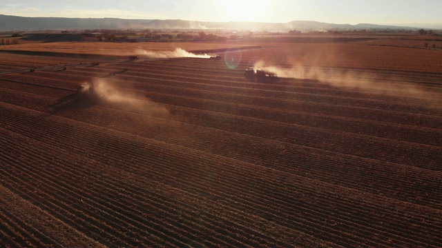 在科罗拉多州西部的日落时分，一架上升/用卡车运回的无人机拍摄了一片满是不同类型拖拉机的玉米地视频素材