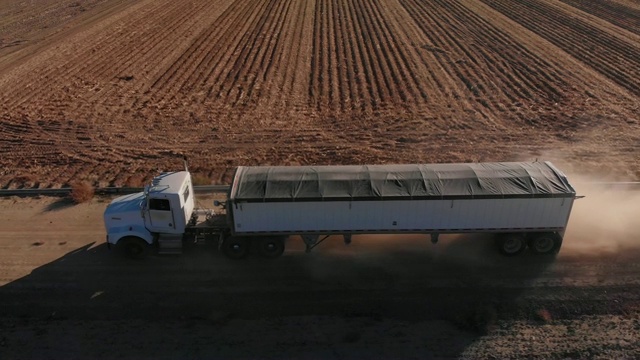 一架无人机在农场的玉米田旁拍摄到一辆在收获时运输玉米的有盖谷物半卡车视频下载