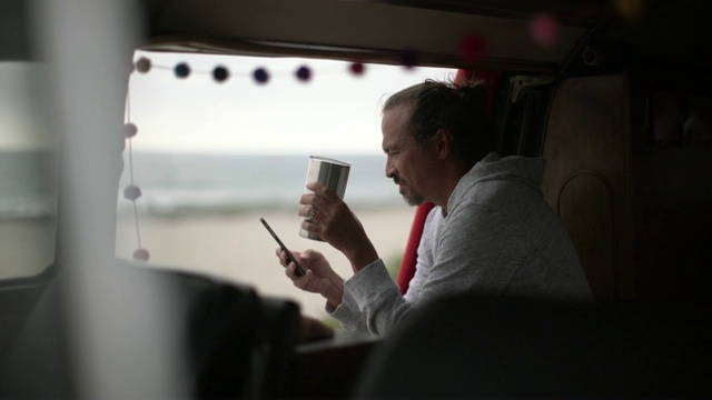 一个在露营车里喝咖啡发短信的成熟男人视频下载