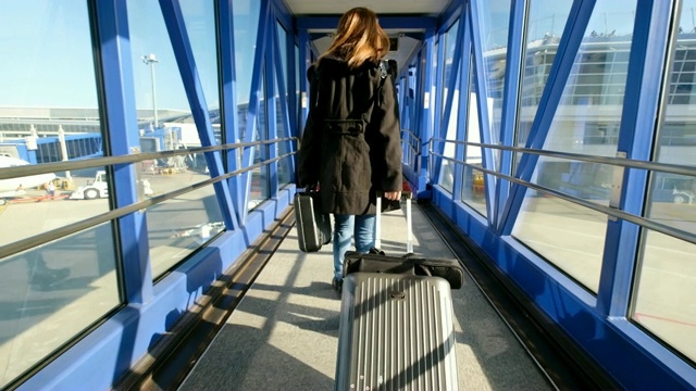 4K移动镜头:亚洲女子在国际机场的飞机停靠处拖着行李。当她到达目的地时视频下载