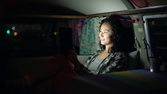 一个年轻女人晚上在她的露营车里鬼混视频素材