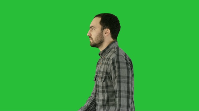 自信随意的男人走在绿色屏幕上，色度键视频素材