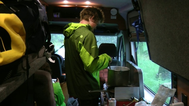 一个年轻人在露营车里做牛排晚餐。视频下载