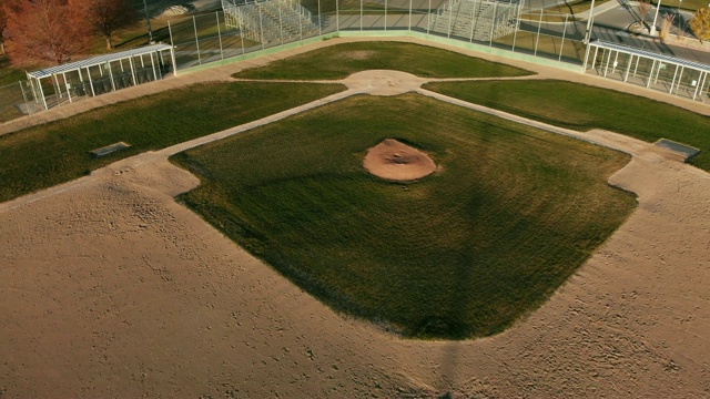 上升卡车返回无人机拍摄的一个空的棒球钻石/球场在日落/日出在一个阳光明媚的日子视频下载