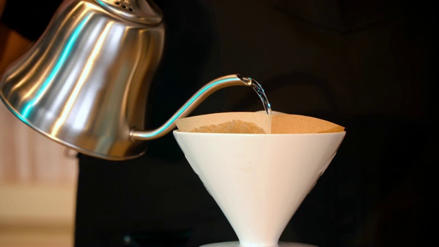咖啡师将热水通过纸过滤器倒入一壶咖啡中视频下载