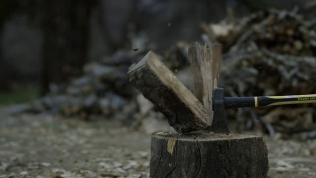 黄昏时分，在柴堆旁边，一把斧头把一根木头劈成两半视频素材