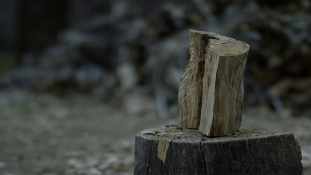 黄昏时分，在柴堆旁边，一把斧头把一根木头劈成两半视频素材