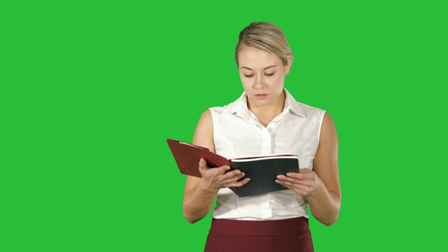 女人拿着书或笔记本，在绿色屏幕上大声读着什么视频素材