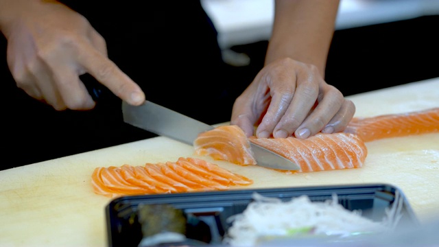 厨师正在把鲑鱼片切好，放在一个漂亮的盘子里。视频素材