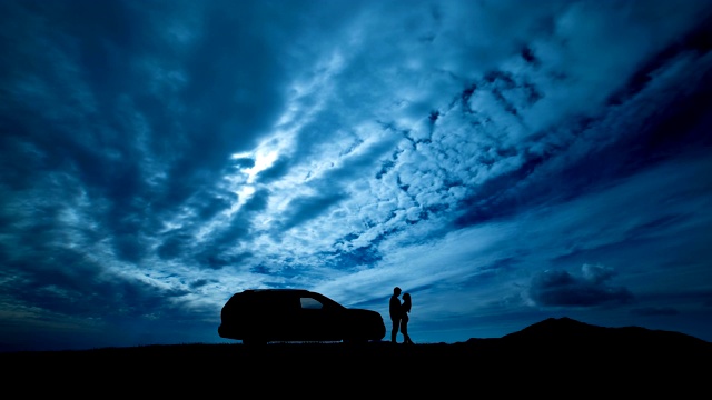 一个男人和一个女人站在一辆车旁边，背对着云流。时间流逝视频下载