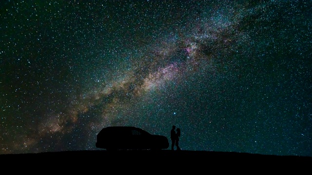这对夫妇站在一辆汽车旁，天空中闪烁着星星。时间流逝视频素材