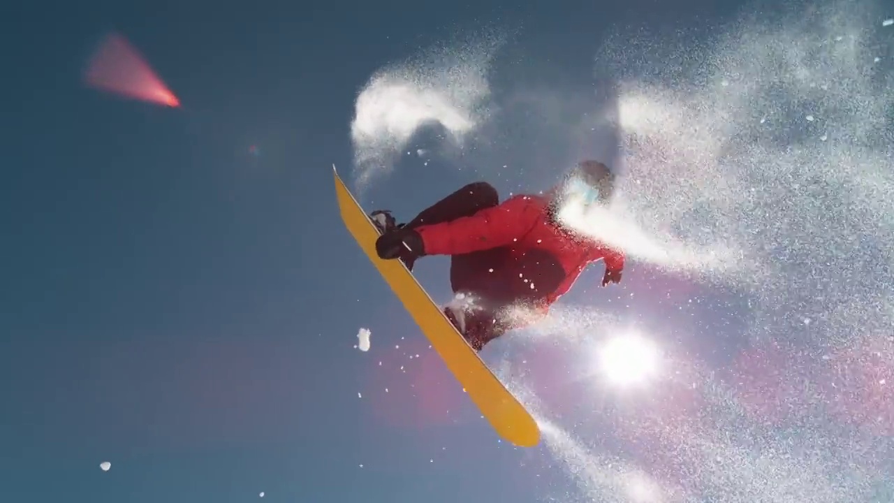 慢动作近景:滑雪板跳跃和飞过太阳在晴朗的蓝色天空视频素材