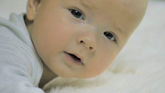 一个新生儿躺在他的腹部微笑着看着镜头的特写。视频素材