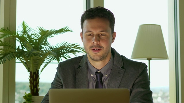 企业家坐在办公桌前用笔记本电脑和智能手机工作视频素材