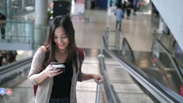 亚洲女性在机场旅行时使用手机视频素材