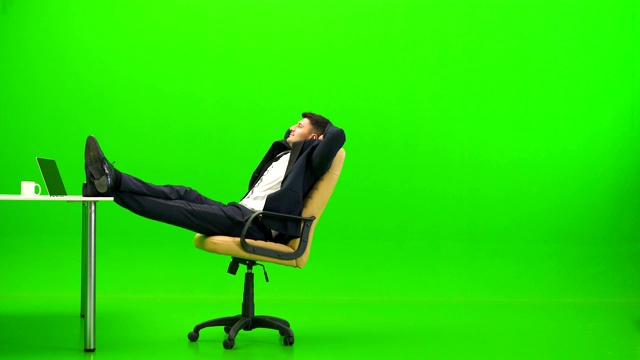 在绿色背景的桌子旁放松的男人视频素材