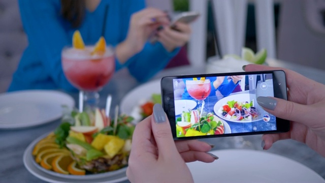 智能手机在博主女人的手使照片健康素食在午餐期间为社交网络，特写视频下载