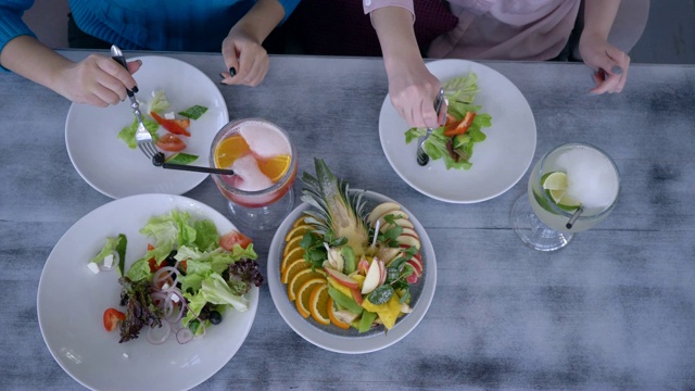 健康的减肥食品在新鲜的聚会上，顶部视图年轻女性有晚餐和餐桌上的饮料和水果沙拉视频下载