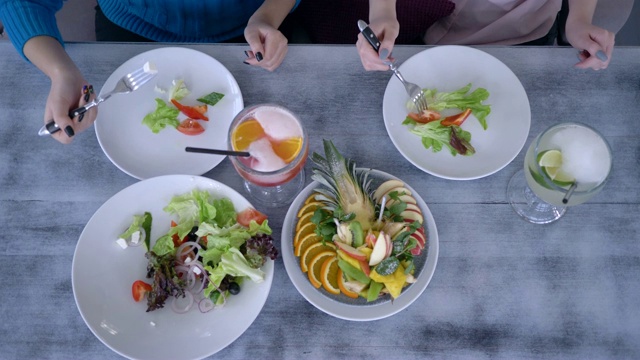 餐桌上有健康的食物和玻璃杯，人们用叉子吃盘子旁边的手视频下载
