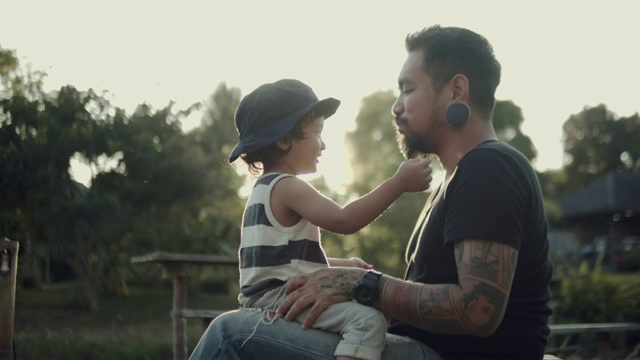 年轻的亚裔父亲抱着他的孩子在湖景视频素材