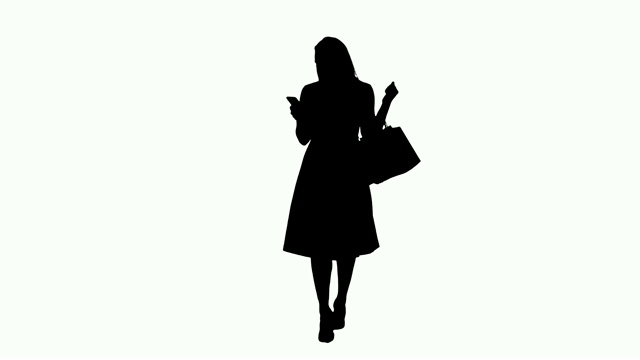 剪影购物的女人拿着包，一边走一边用智能手机发短信视频下载