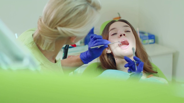 牙医给年轻女子麻醉。女牙医正在用口镜视频素材