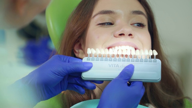 医生检查病人牙齿的洁白程度。近距离选择牙医的颜色视频下载