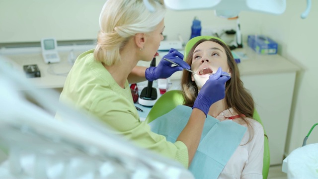 牙科保健员用口腔镜和牙科探针检查病人的牙齿视频素材