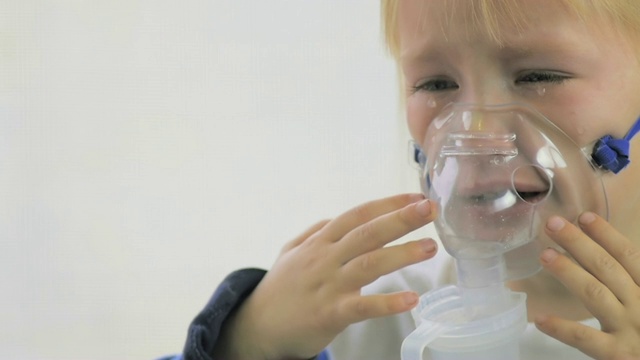 4岁女孩在医院通过吸入器面罩做呼吸程序的慢镜头。视频下载