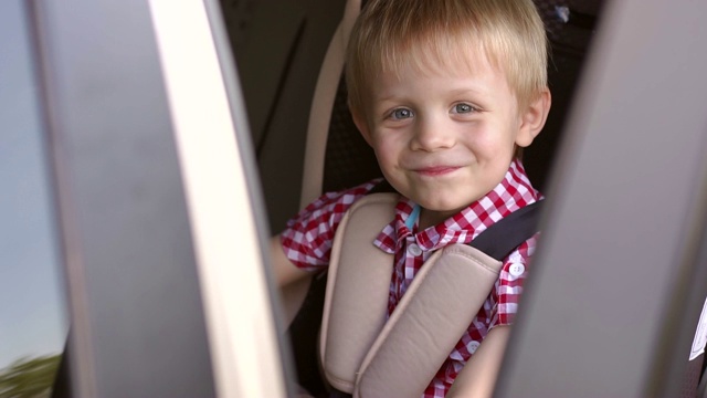 特写的快乐小男孩的脸在汽车座椅在夏天。孩子的安全。视频素材