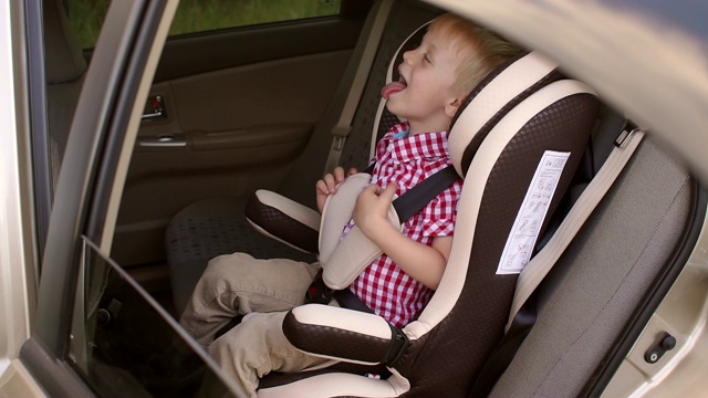 一个快乐的笑着的男孩在汽车座椅上的肖像。视频素材