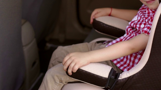 孩子坐在汽车座椅上，他的手放在椅子的扶手上视频素材