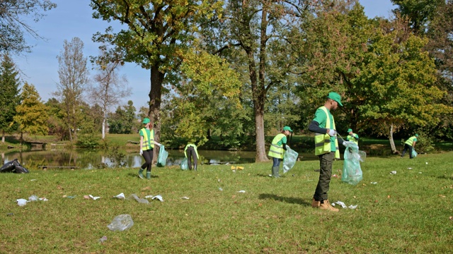 TIME-LAPSE志愿者在活动结束后在池塘边的草地上捡垃圾视频下载