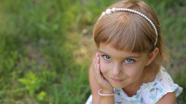 微笑的小女孩的肖像在绿色的草地上的背景公园。色彩差异视频下载
