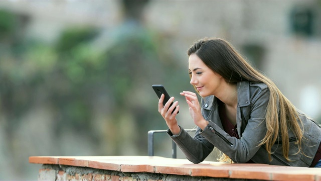 一个兴奋的女人在阳台上查看手机内容视频素材