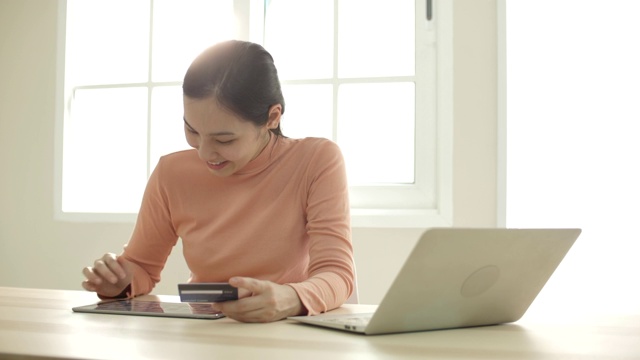 年轻的亚洲女性在家里用平板电脑在线购物视频素材