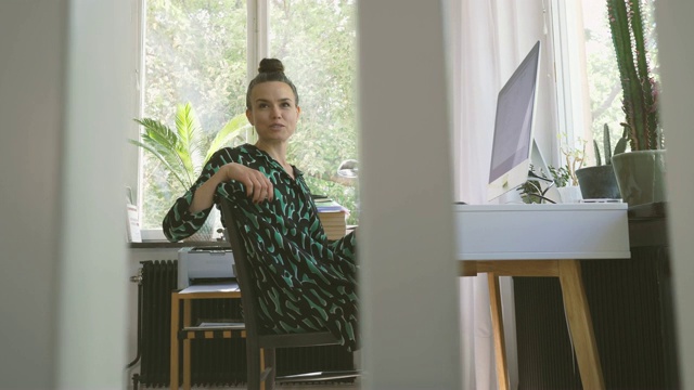 坐在家里办公室的办公桌前说话的商业女性视频素材