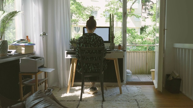 手持拍摄的女商人使用手机和电脑在家庭办公室视频素材