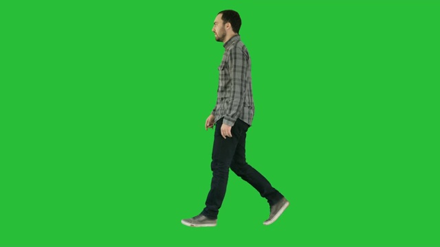 年轻随意的男人走在绿色屏幕上，色度键视频素材