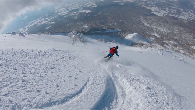 镜头:在风景优美的偏远地区，沿着男游客滑雪下山。视频素材