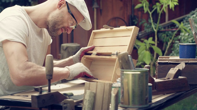 花园DIY。男人打磨木制家具。视频素材