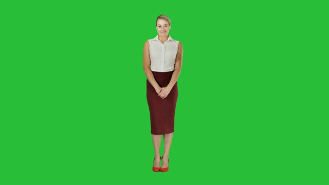 迷人害羞的女商人站在绿色屏幕上看着镜头视频下载