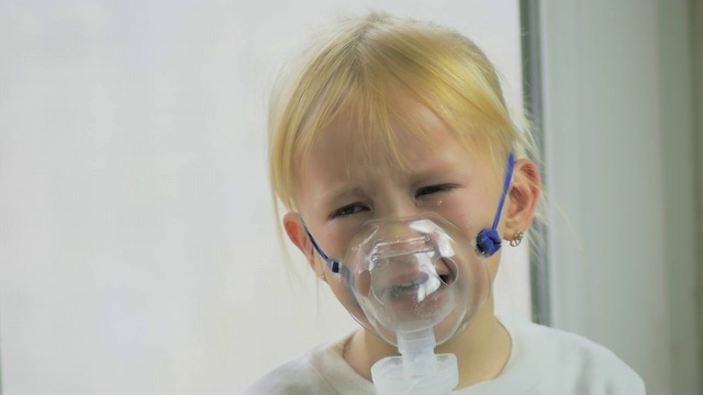 四岁女孩戴着面具通过吸入器在医院里缓慢呼吸。视频素材
