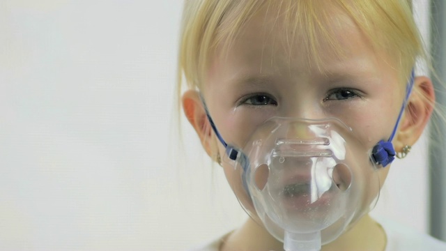 一个四岁的女孩在医院通过吸入器呼吸气体的特写镜头。视频素材