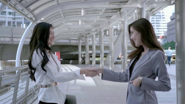两个年轻的亚洲女商人握手完成一笔交易。协议，成功或问候的概念。视频素材